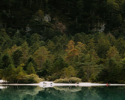 A calm lake surrounded by dense green forest in Northern Italy